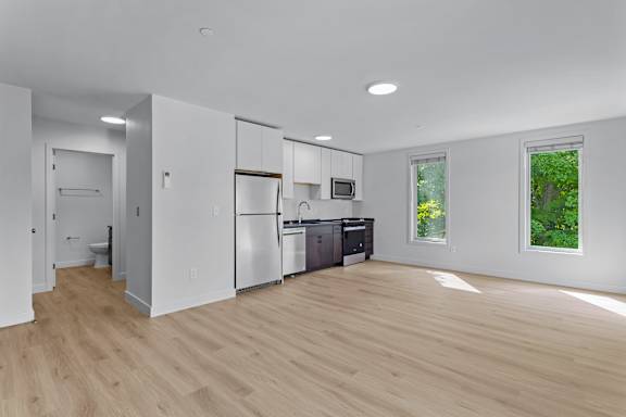 a renovated kitchen with white walls and wood floors