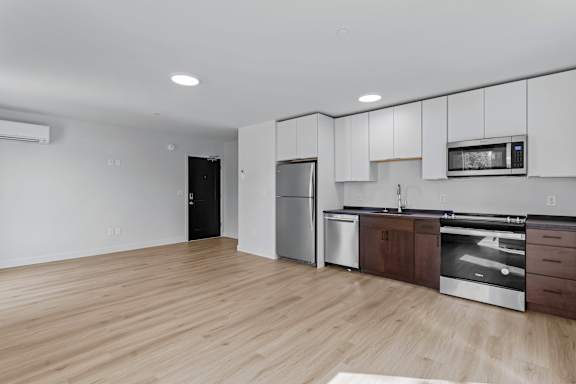 an empty kitchen with white cabinets and stainless steel appliances