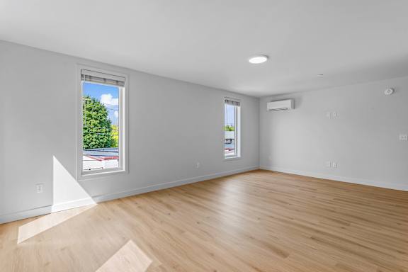 an empty living room with wood floors and a window