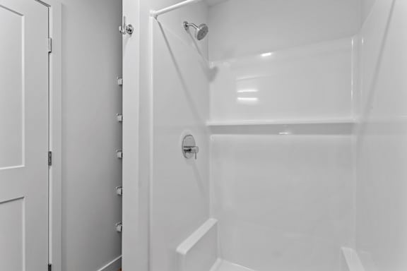 a bathroom with a shower and a white door