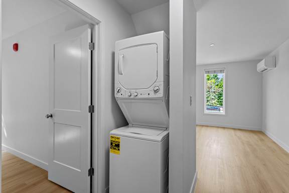a washer and dryer in a white room with a door and a window