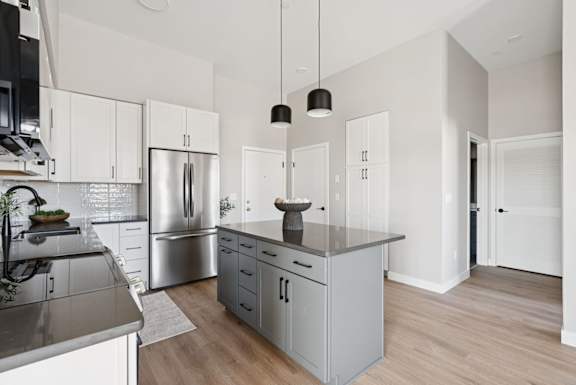 A modern kitchen with a stainless steel refrigerator and a grey island.