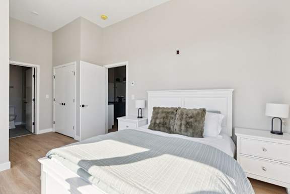 A bedroom with a large bed, nightstands, and a wardrobe.