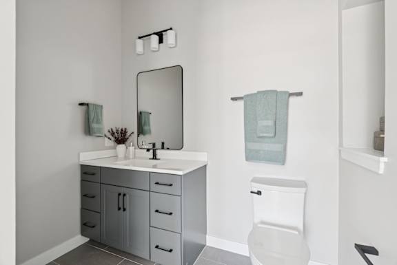 A bathroom with a white toilet and a white sink with a mirror above it.