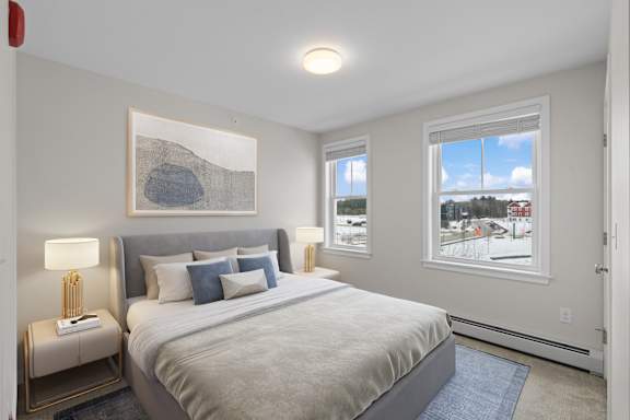 A bedroom with a large bed and a view of the outside through the window.