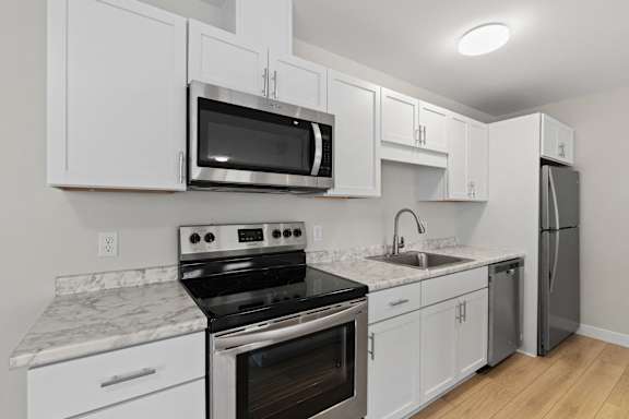 A kitchen with white cabinets and appliances.