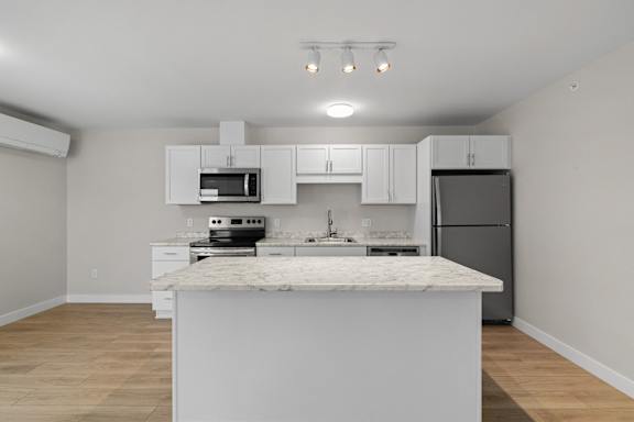 A kitchen with a marble countertop and white cabinets.