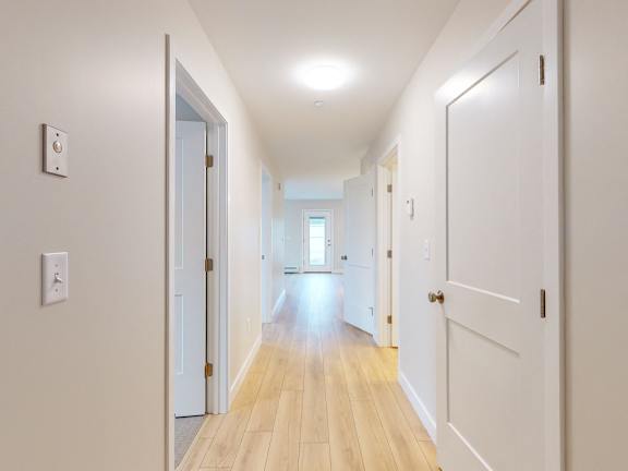 A long hallway with white walls and wood floors.