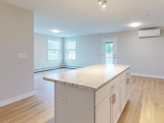 A kitchen with a marble countertop and wooden flooring.