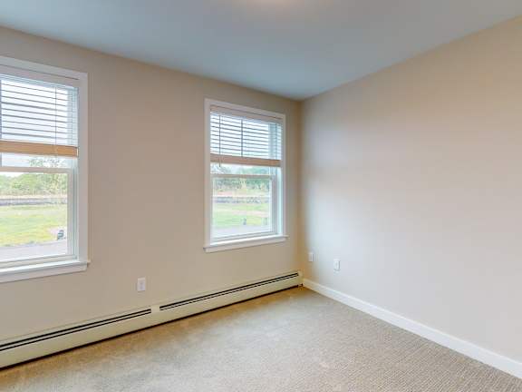 A room with two windows and a carpeted floor.