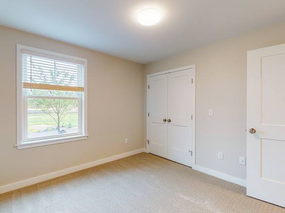 A room with a window, two doors, and a carpeted floor.