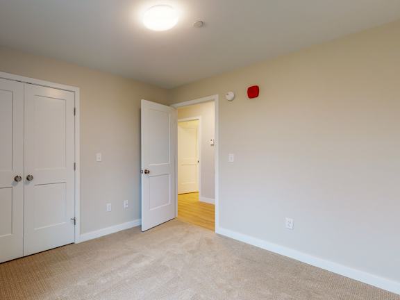 A room with a white door, a white wall, and a red square on the wall.