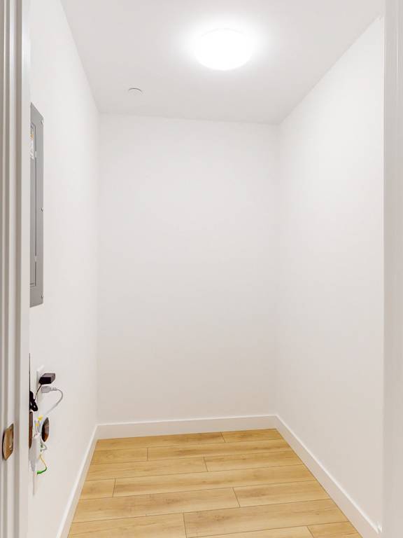A hallway with a light on the ceiling and a door on the left.