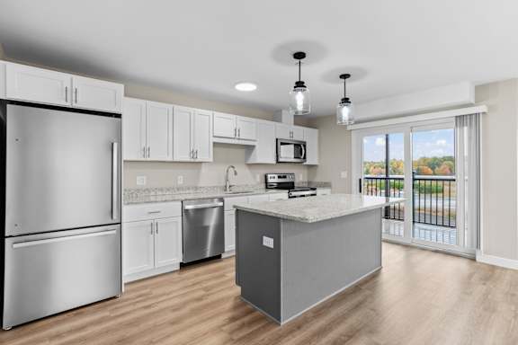 Kitchen With Island, Stainless Steel Appliances &amp; Sliding Glass Door To Balcony