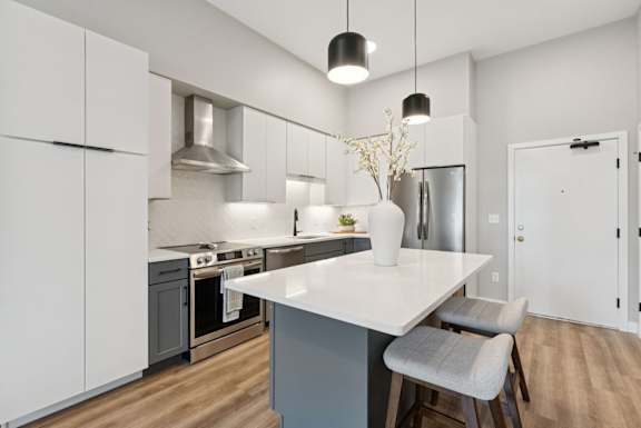 A modern kitchen with a white countertop and grey cabinets.