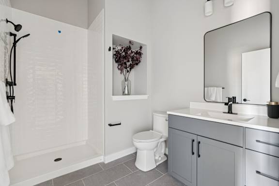 A white bathroom with a toilet, sink, and shower.