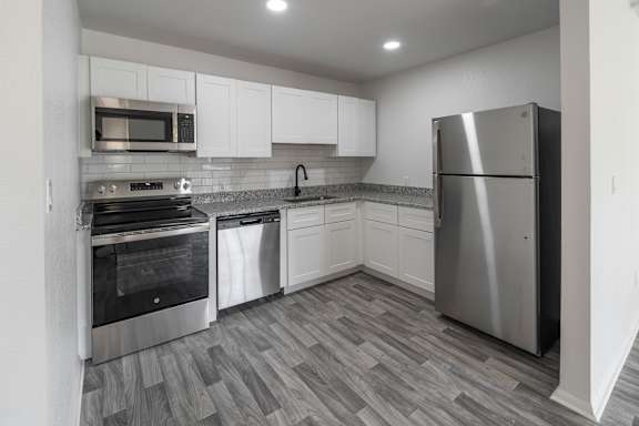 A kitchen with a refrigerator, oven, and microwave.