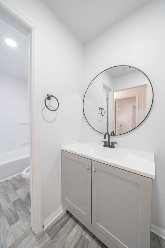 A bathroom with a white sink and a round mirror.