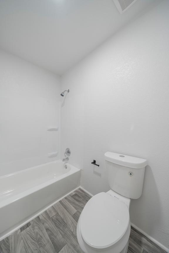 A white toilet in a bathroom with a white tub.