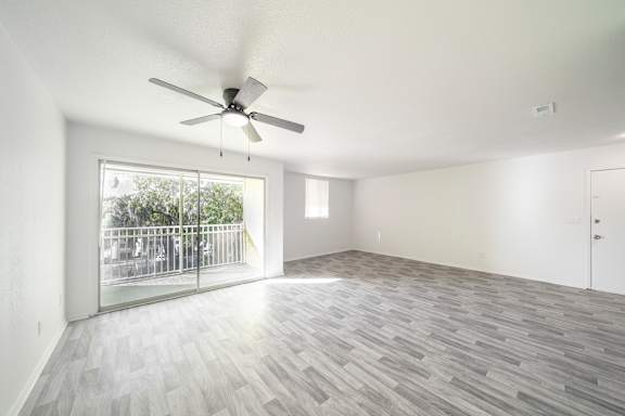 A room with a ceiling fan and a sliding glass door leading to a balcony.