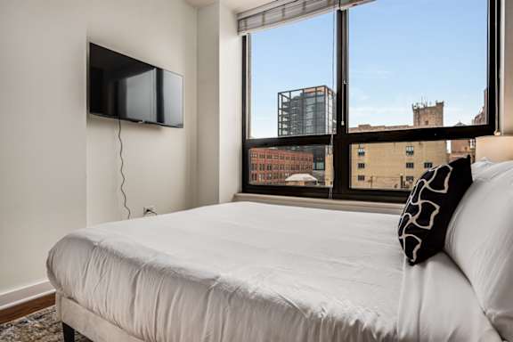 A bedroom with a large bed and a flat screen TV mounted on the wall.