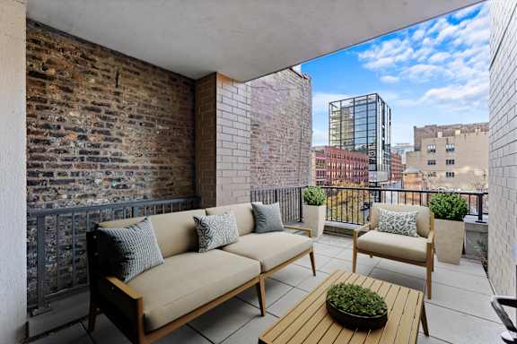 A balcony with a couch, chairs, and a table with a plant on it at Chateau on Wells, Chicago