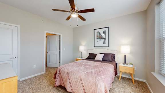 A bedroom with a bed, nightstand, and a ceiling fan at The Slate, Jeffersonville, 47130