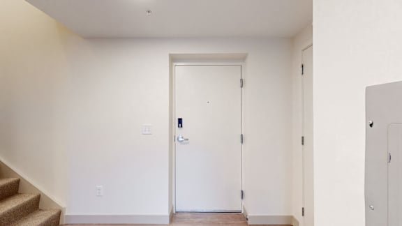 A white door with a black handle is in a room with white walls.