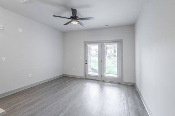 A room with a ceiling fan and sliding glass doors.