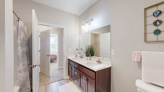 A bathroom with a white toilet, a sink with a mirror, and a shower with a curtain at The Slate, Jeffersonville, 47130