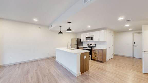 A kitchen with a white counter top and wooden floors.