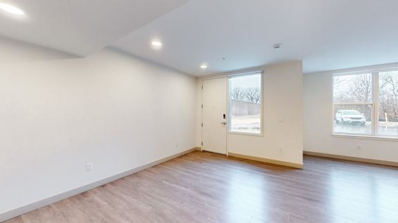 A large empty room with wooden floors and a door.