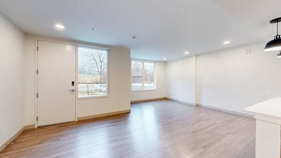 A room with a white door and a window with a view of a tree and a building outside.