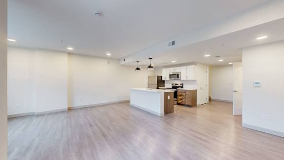 A spacious room with a kitchen area in the background.