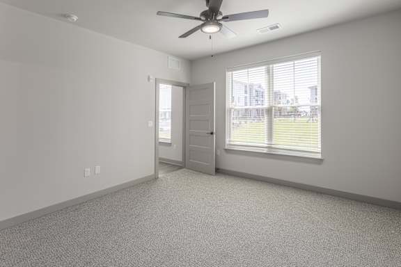 A room with a ceiling fan and a door leading to a balcony at Arbour Place Apartments, Jeffersonville, IN