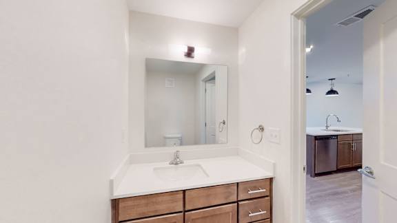 A bathroom with a sink, mirror, and wooden drawers.