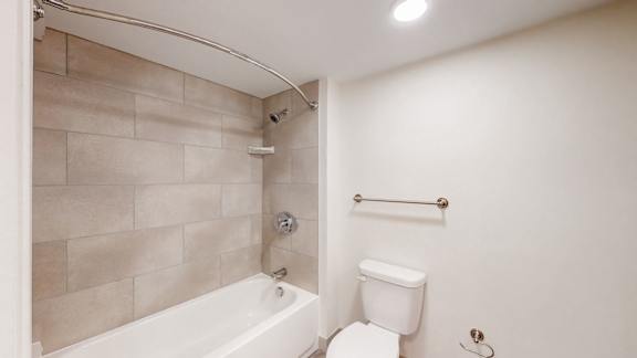 A white toilet sits next to a white bathtub in a bathroom.