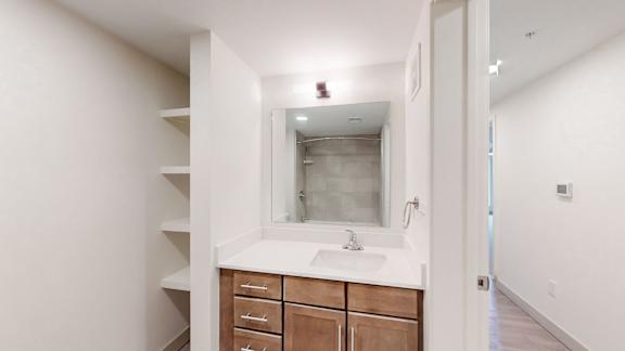 A bathroom with a sink, mirror, and wooden drawers.