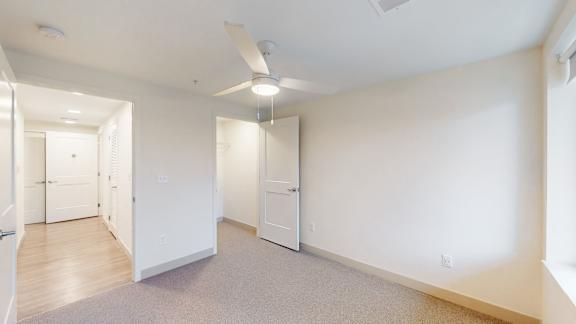 A spacious room with a ceiling fan and carpeted floor.