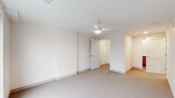 A spacious room with a ceiling fan and carpeted floor.