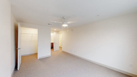 A large, empty room with a door on the left and a window on the right.