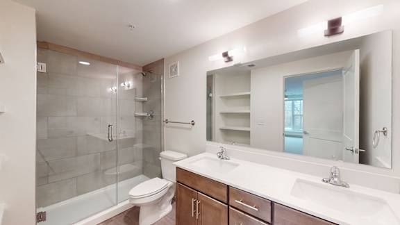 A bathroom with a white sink, toilet, and a glass shower stall.