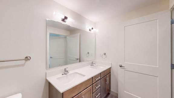 A bathroom with a sink, mirror, and towel rack.