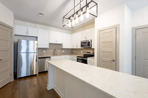 A modern kitchen with a white marble countertop and stainless steel appliances.
