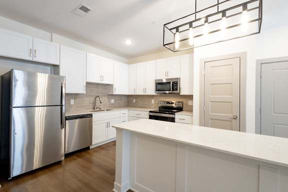 A modern kitchen with a stainless steel refrigerator and white cabinets.