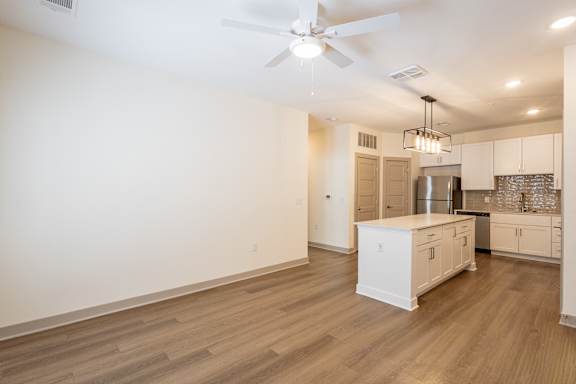 A spacious kitchen with white cabinets and a wooden floor.