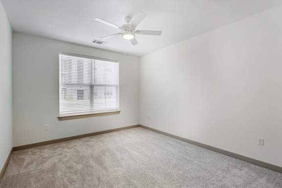 A room with a ceiling fan and a window with blinds.