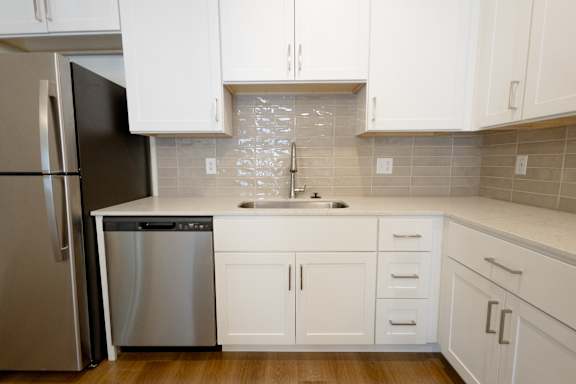 A kitchen with white cabinets and a black fridge.