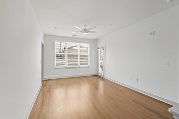 A room with a ceiling fan and wooden flooring.