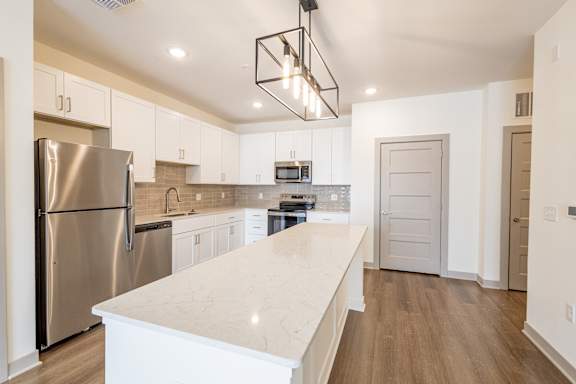 A kitchen with a refrigerator, microwave, and oven.